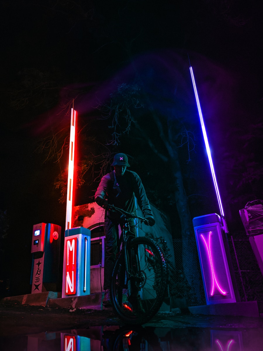 a man riding a motorcycle next to a neon sign